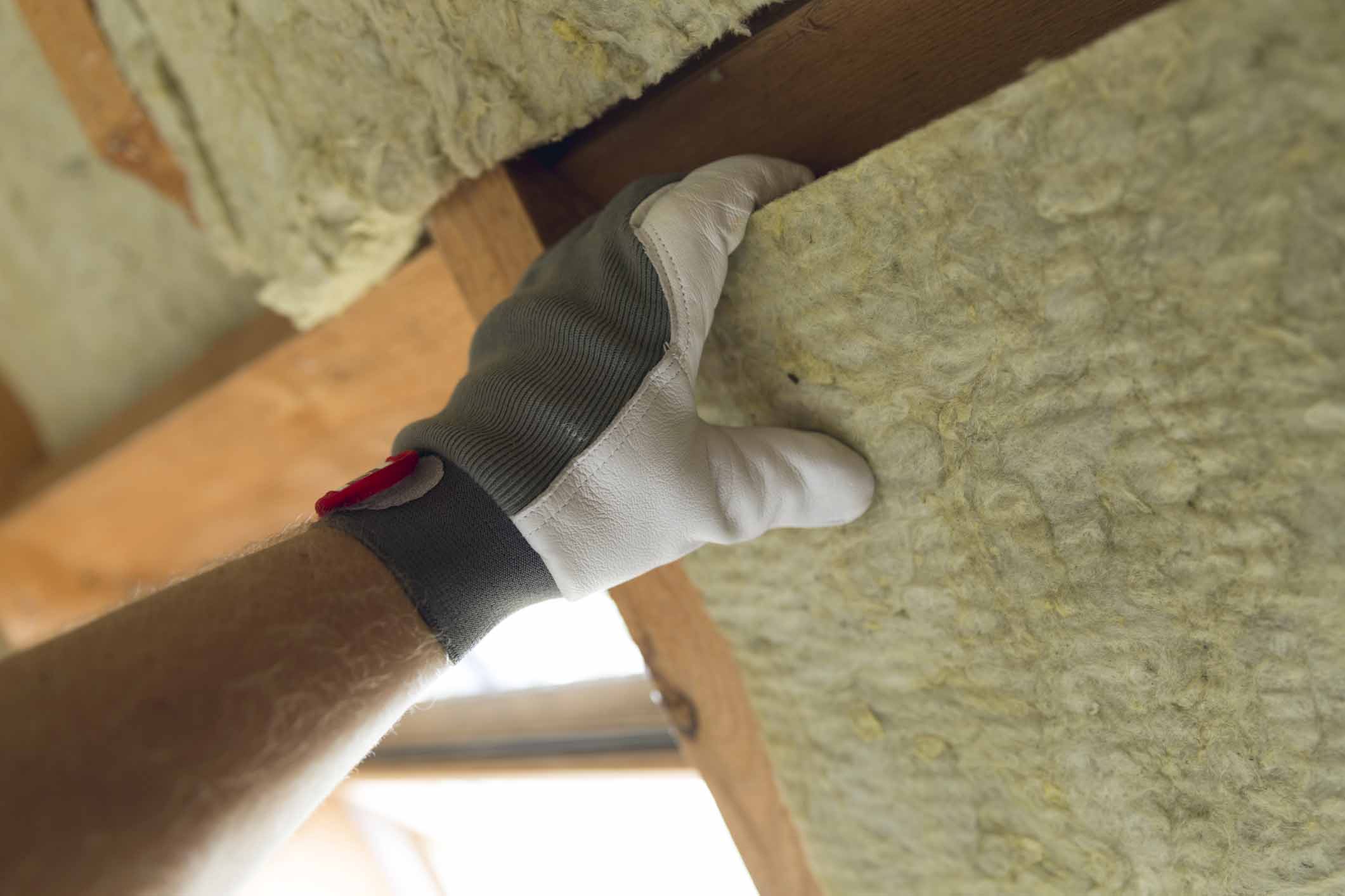 Man installing thermal roof insulation layer - using mineral wool panels. Attic renovation and insulation concept